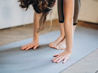 Kvinde bøjer sin krop fremover på yogamåtte